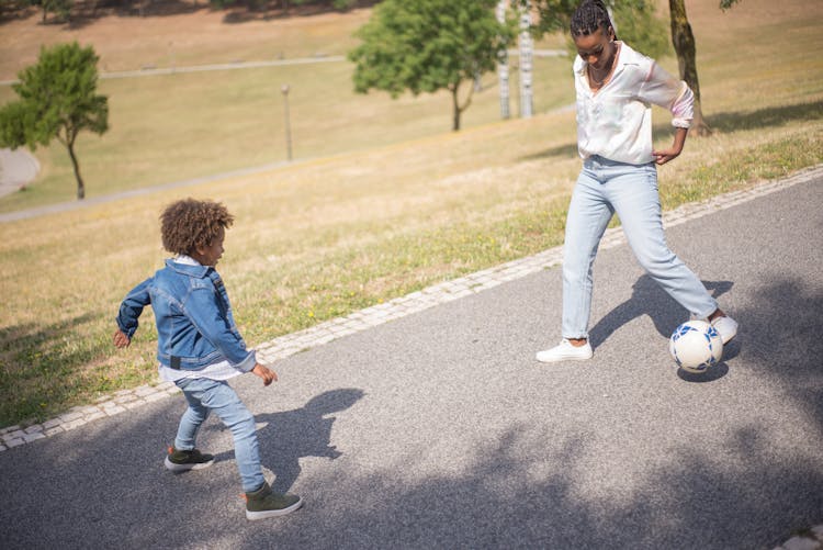 Mother And Son Playing Soccer On Gray Concrete Floor