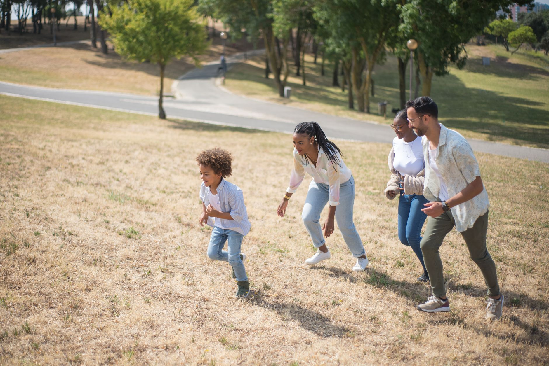 減重遇家庭飲食衝突?實用解法平衡個人與家人 A family of four enjoys a playful day in a sunny park setting, running uphill together.
