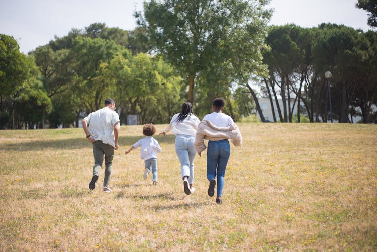 A Family Walking On Grass Field