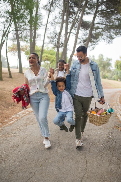 Free Warm family outing with parents and children laughing and playing in a scenic park setting. Stock Photo