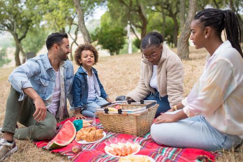 Free A diverse family enjoying a picnic on a sunny day outdoors in Portugal, featuring watermelon and croissants. Stock Photo