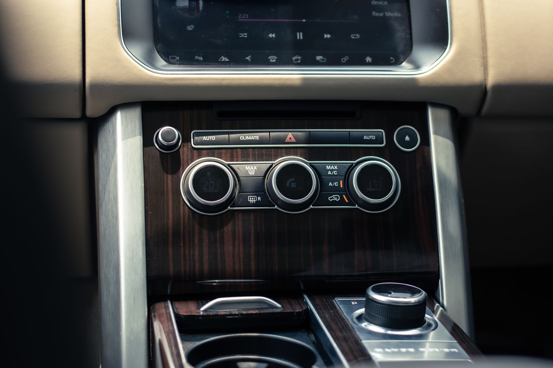 Luxury car dashboard interior featuring climate and audio controls, sleek design.