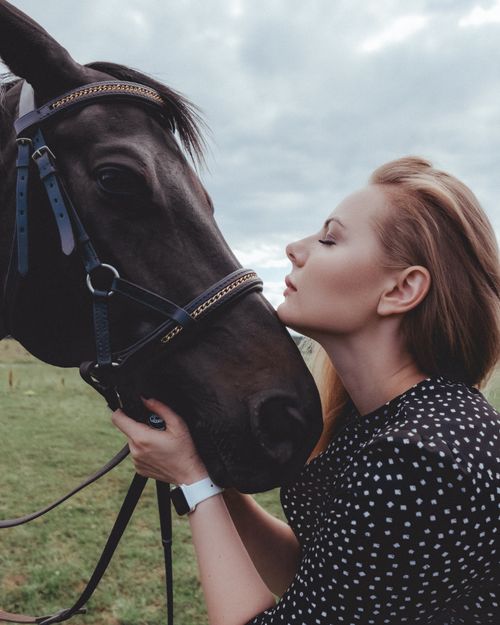 Free A woman affectionately holding a black horse's head in an outdoor setting. Stock Photo