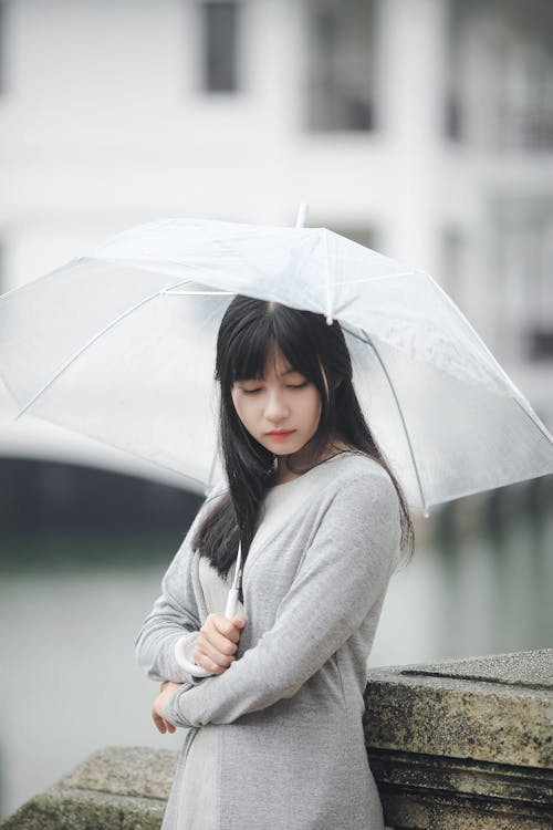 Женщина в сером свитере с прозрачным зонтиком