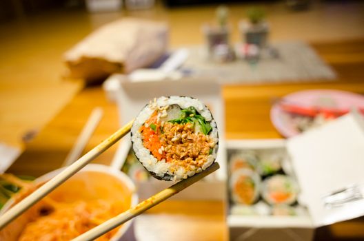 A tempting close-up of a sushi roll held by chopsticks, highlighting fresh ingredients.