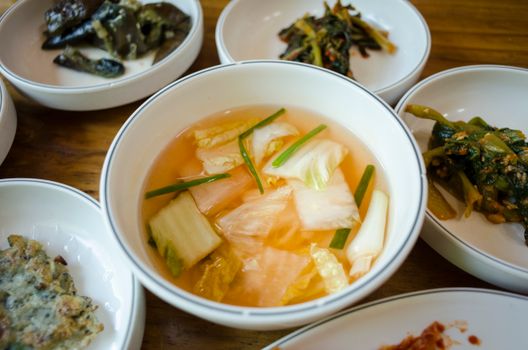 A selection of traditional Korean side dishes served in ceramic bowls on a wooden table.
