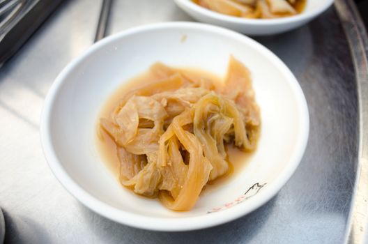 A close-up of a bowl filled with pickled cabbage, presenting a side dish in a white saucer.