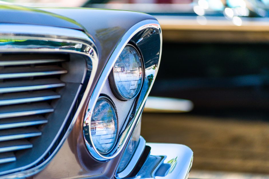 Detailed close-up of a classic car's headlight and chrome grille, showcasing vintage elegance.