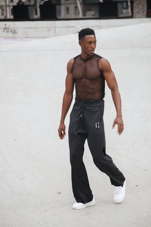 A Man in Black Tank Top and Pants Standing on the Street