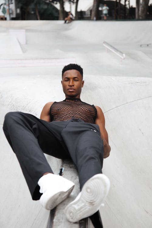 Man in Black Mesh Tank Top Lying on a  Concrete Surface