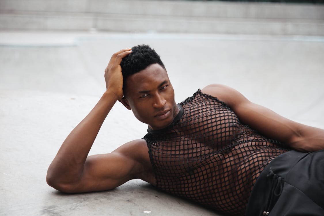 A Man in Black Mesh Tank Top Lying on the Floor with His Hand on His Head