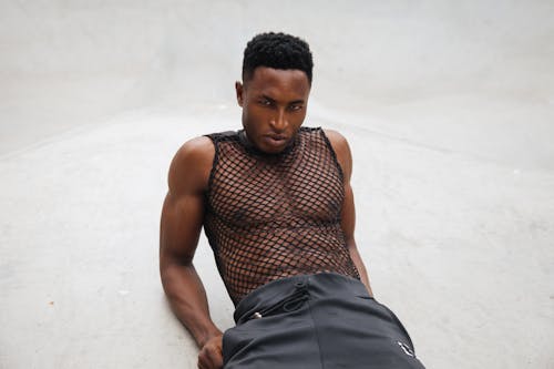 Man Wearing Mesh Tank Top while Posing on White Surface