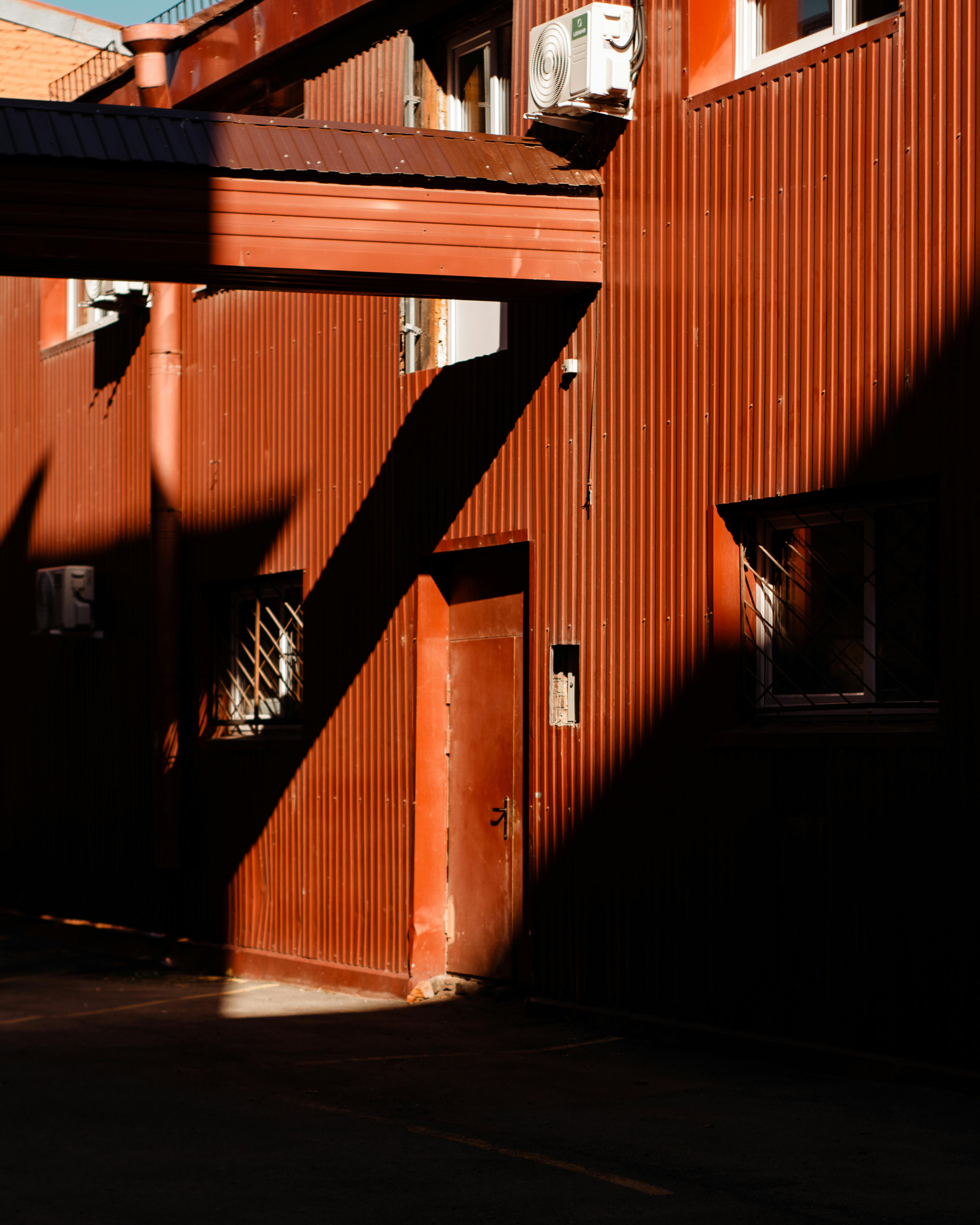 Sunlit red warehouse facade with industrial design elements in evening light.