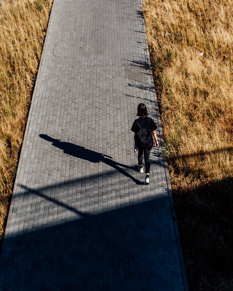 Person Wearing Back Pack Walking On A Block Pavements 