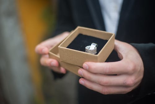 Person Holding a Brown Box with Ring 