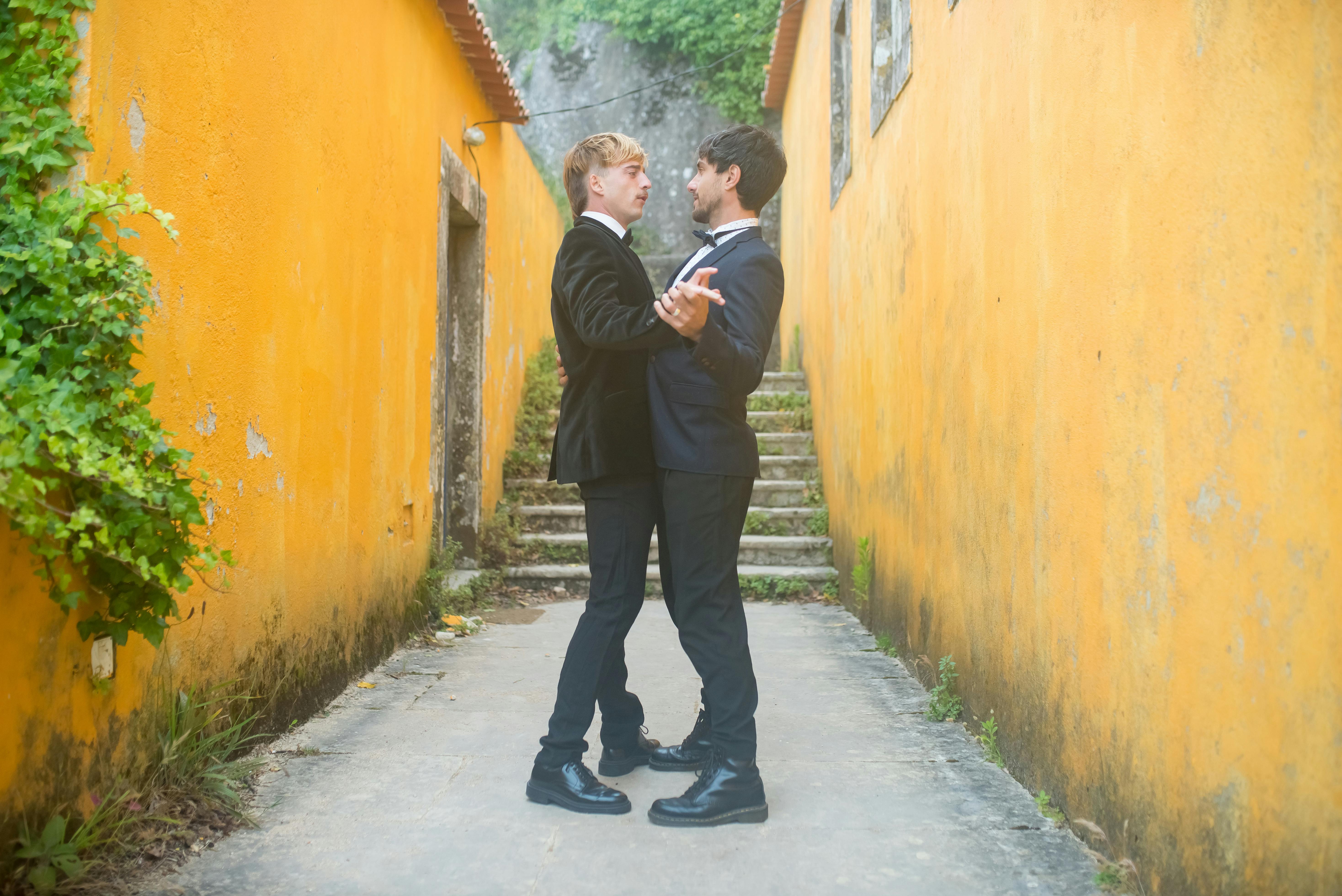 A couple shares a tender moment in a vibrant alley, symbolizing love and celebration.