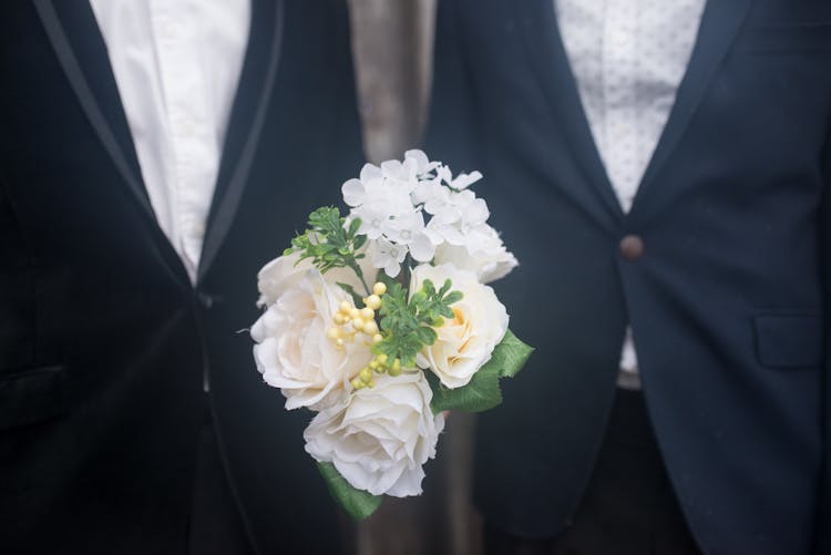 White Flowers In Between People Wearing Black Suits 