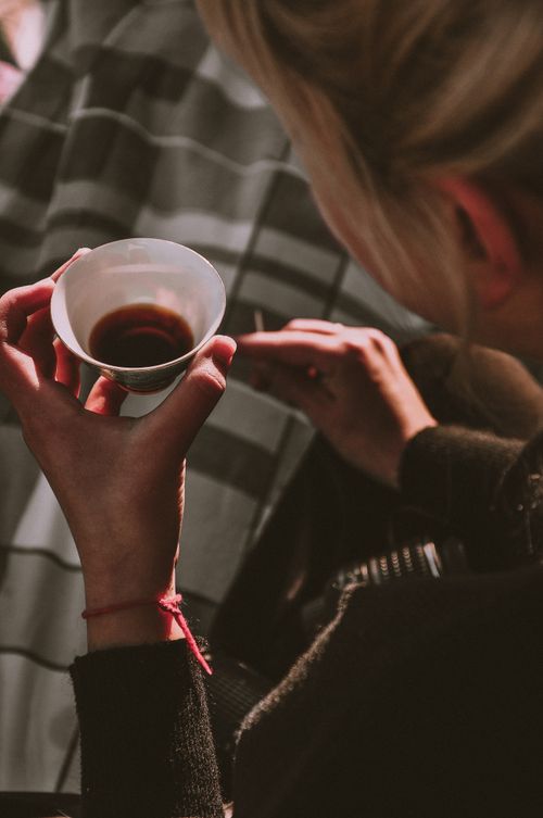 Free A woman holds a cup of hot beverage, captured from a high angle for a cozy and inviting feel. Stock Photo