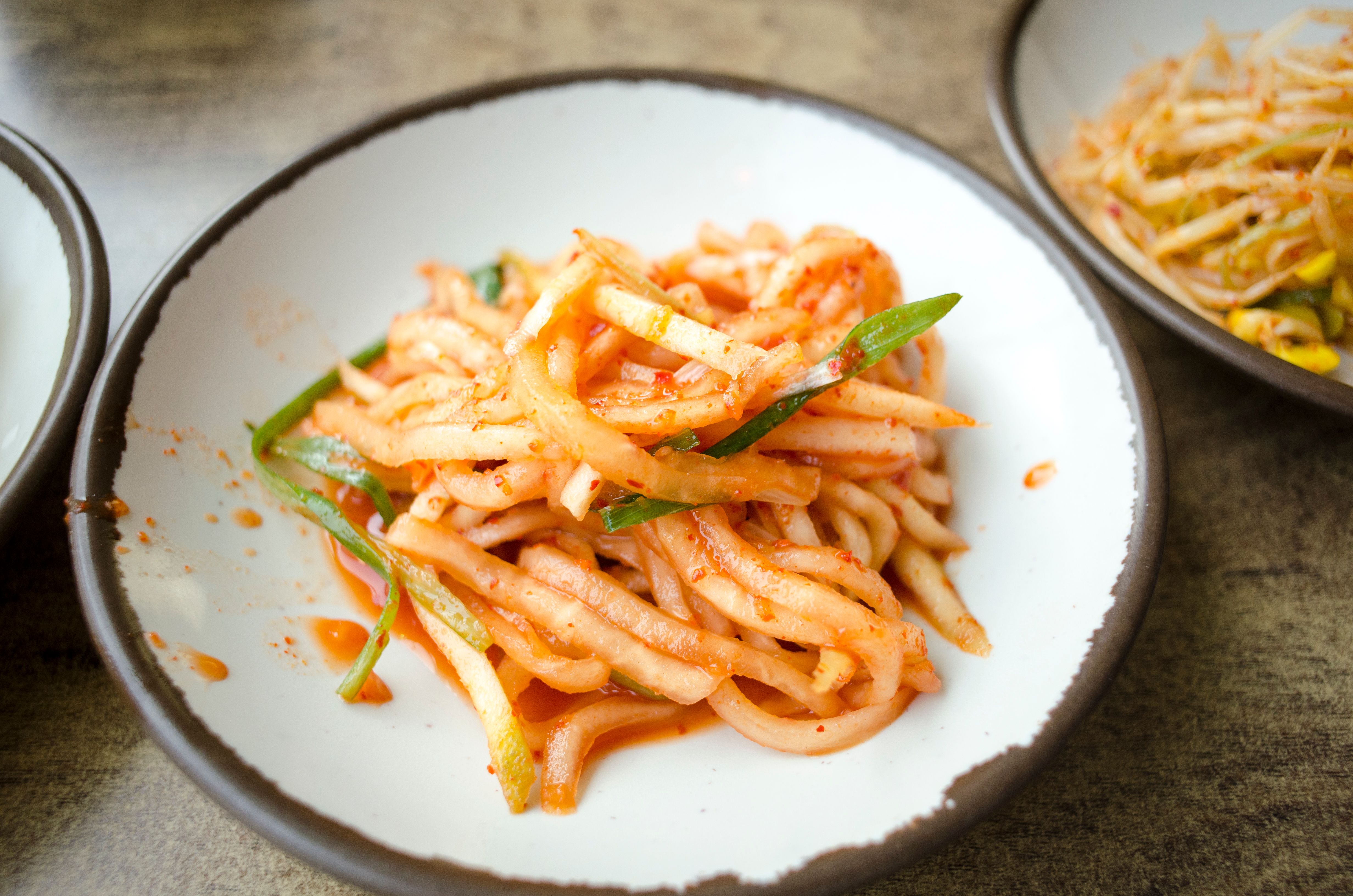 A close-up of Korean spicy radish salad dish served on a ceramic plate, highlighting its vibrant colors and flavors.