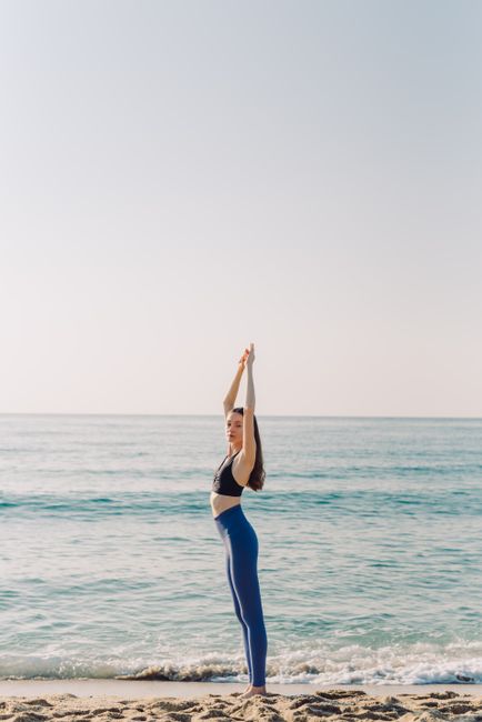 A woman performs a yoga pose on a peaceful beach, capturing wellness and tranquility.