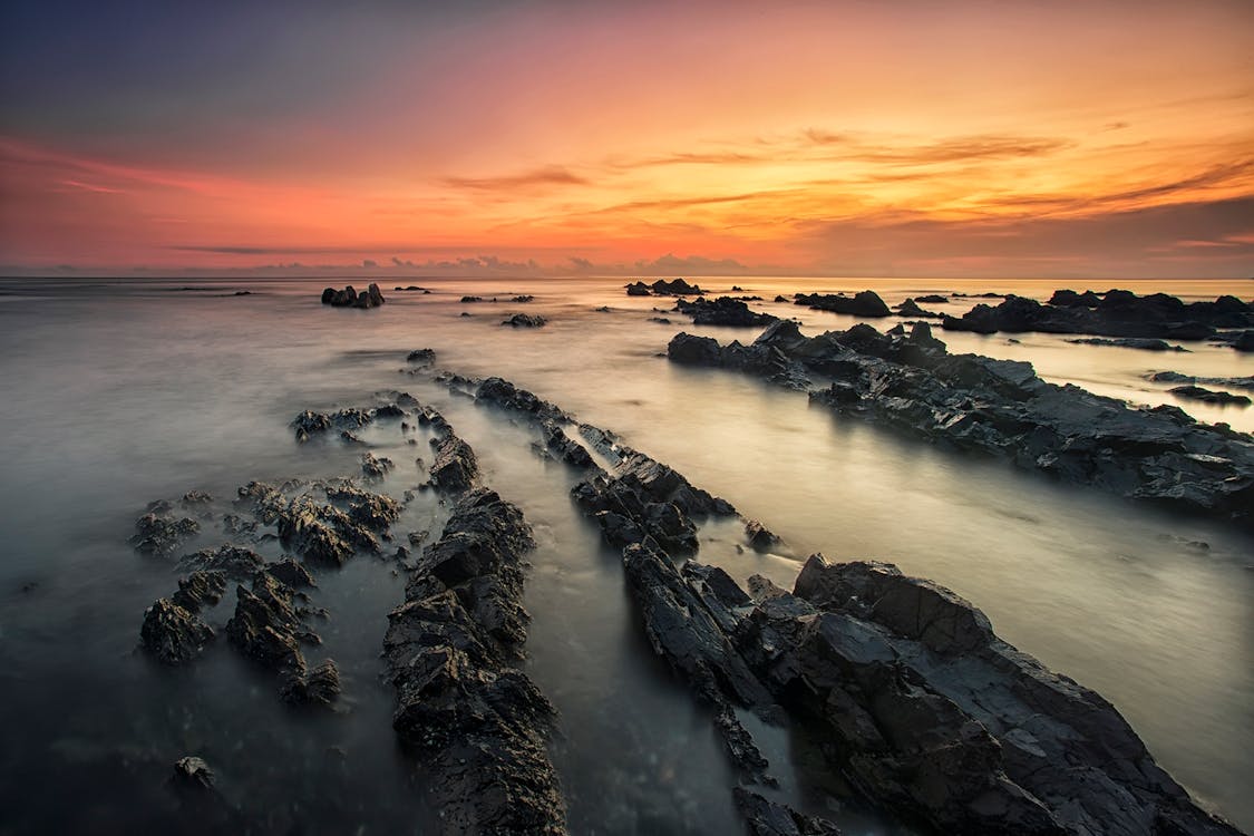 grátis Formação Rochosa No Mar Ao Pôr Do Sol Foto profissional