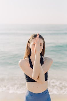 Woman performs Eagle Pose yoga on a sunny beach, embracing mindfulness and tranquility.