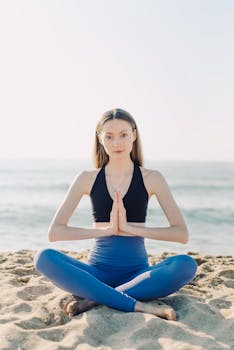 Woman practicing yoga on the beach at sunrise, embracing calm and tranquility.