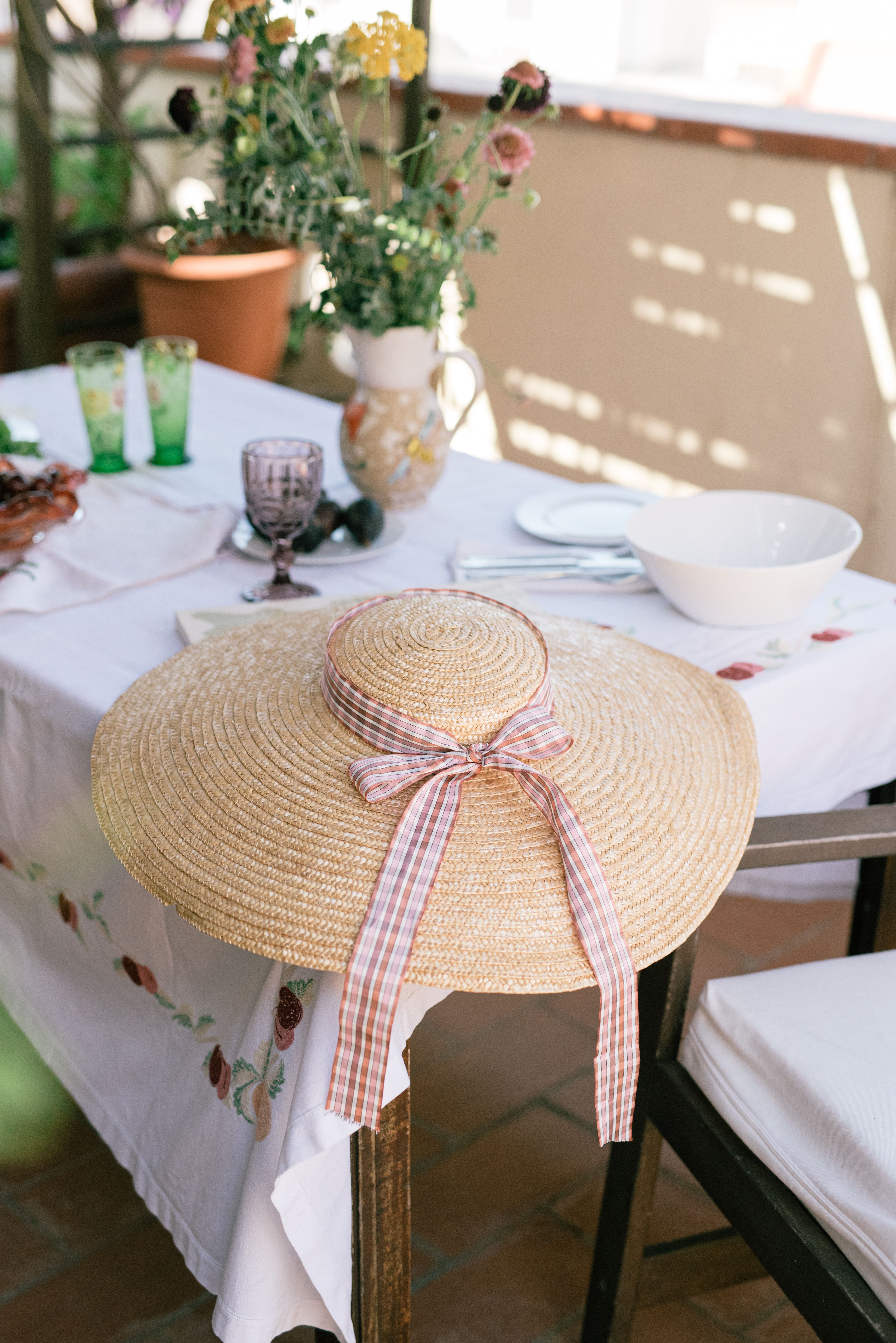 Cozy outdoor dining setup featuring a stylish sun hat on a decorated table.