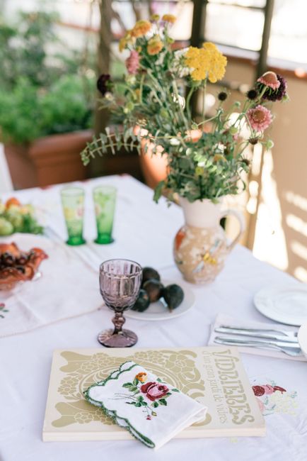 Charming outdoor dining scene with floral vase, book, and glassware on a bright summer day.