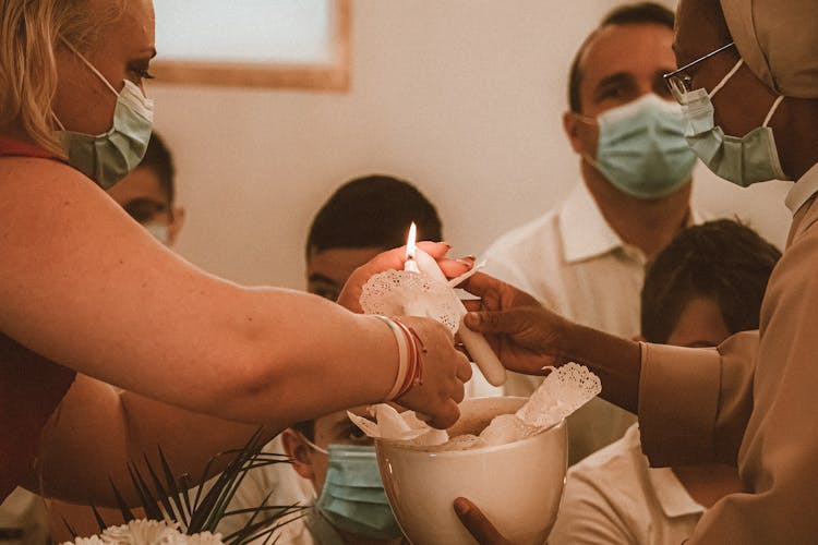 People With Face Masks Lighting White Candles