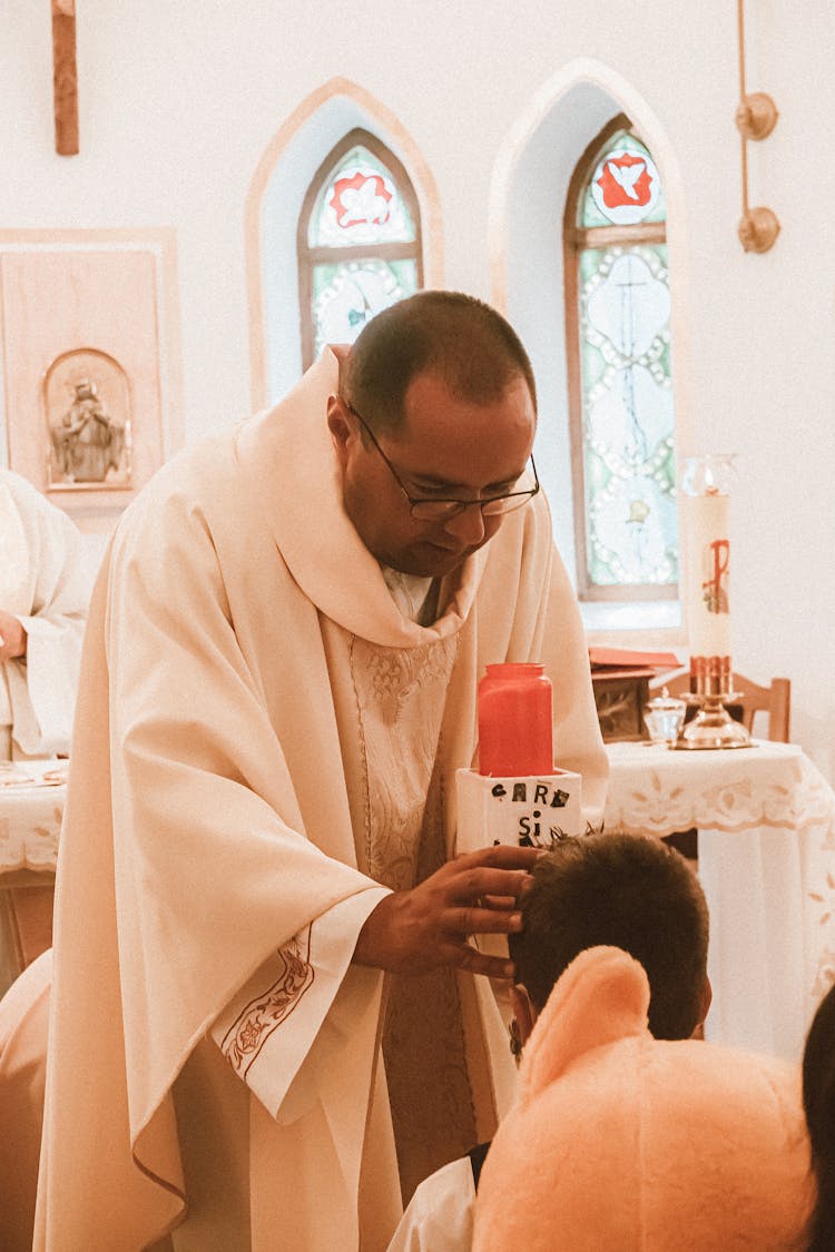 A Priest In White Robe Giving Blessing To A Child