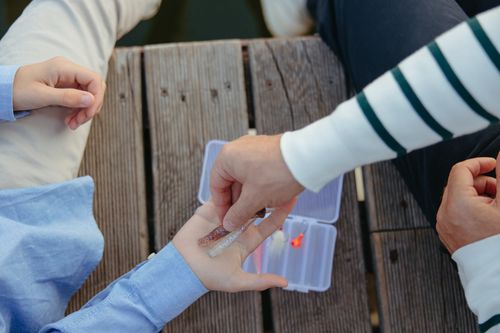 Free Parent and child selecting fishing lures from a tackle box on a wooden dock. Stock Photo