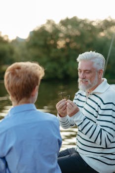 Grandfather and grandson bonding by the river, learning fishing together in a serene outdoor setting.