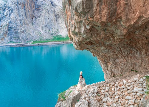 Woman in White Dress Sitting on Rocky Cliff