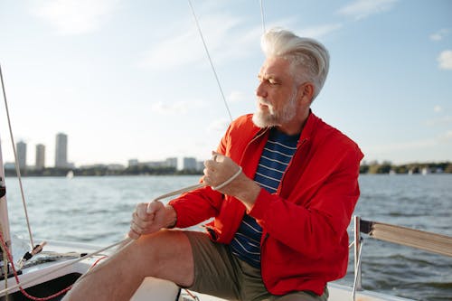 Man in Red Jacket Sitting on Boat