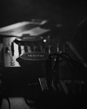 Artistic black and white photo of a DJ mixer setup, capturing the mood and ambiance of a music studio.