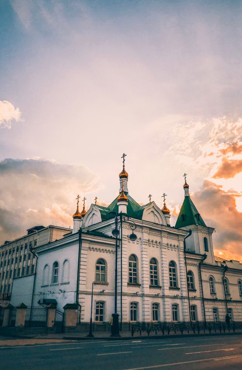 Free Low-angle view of a historic white building with green domes under a dramatic sunset sky. Stock Photo