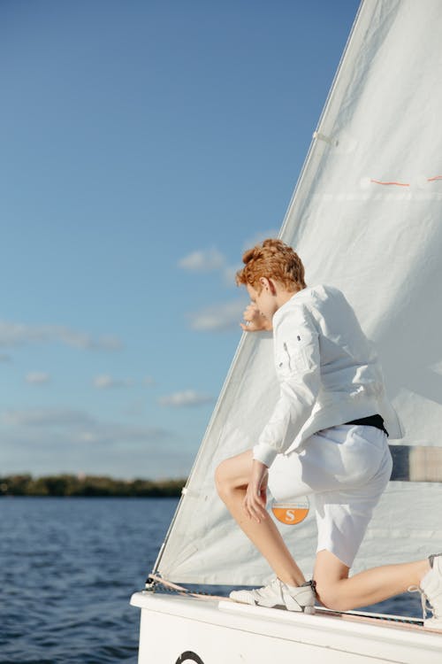 Woman in White Long Sleeve Shirt and White Shorts Riding a White Boat