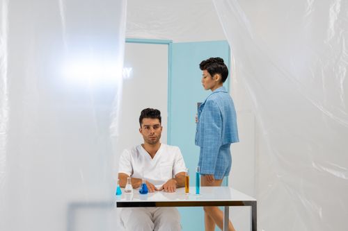 Free Two researchers in a futuristic lab setting with flasks on display. Stock Photo