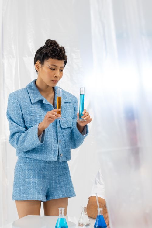 Free Woman in blue outfit holding test tubes with colored liquids in a modern laboratory. Stock Photo