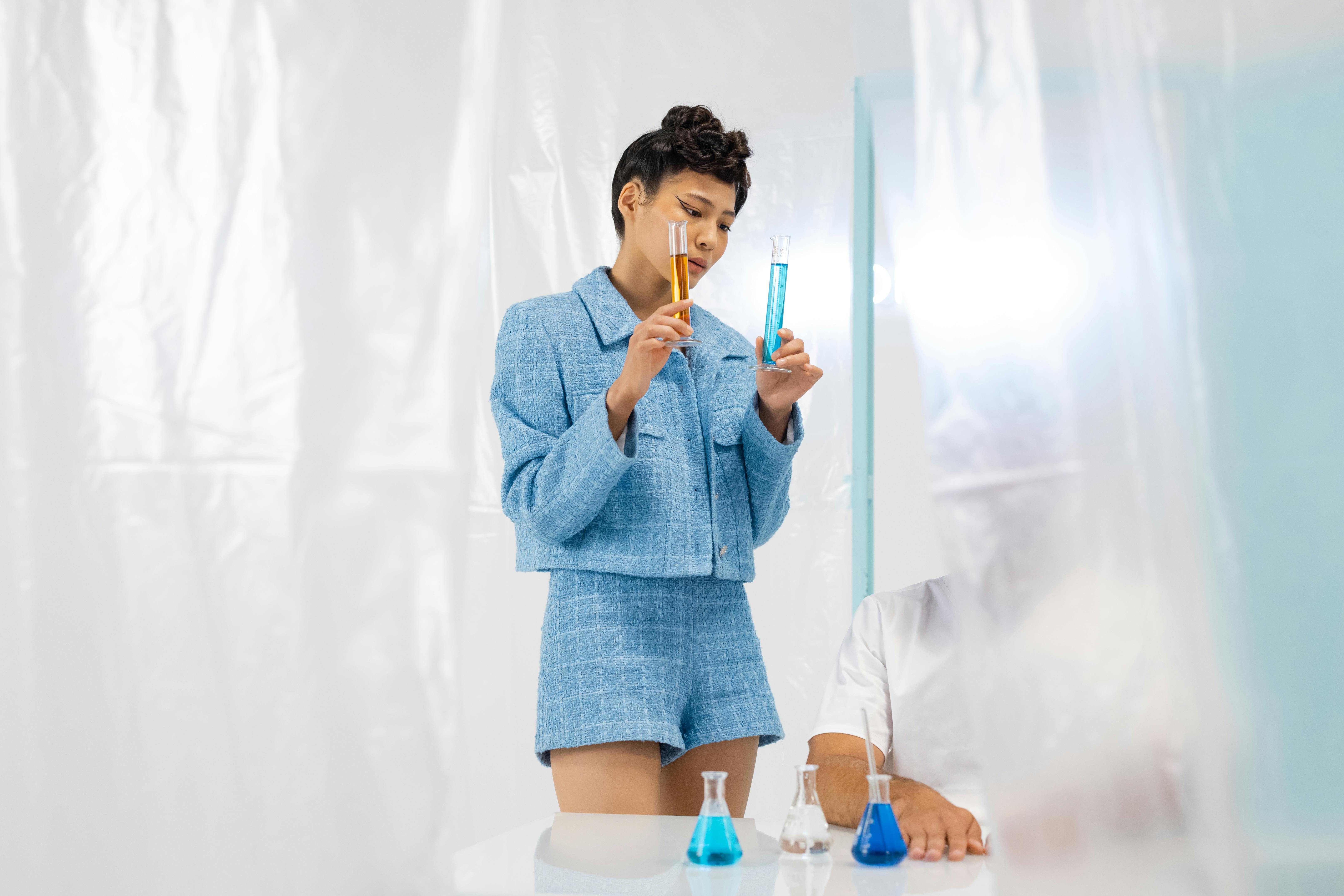 Fashionable young scientist examines colored liquids in a modern lab setting.
