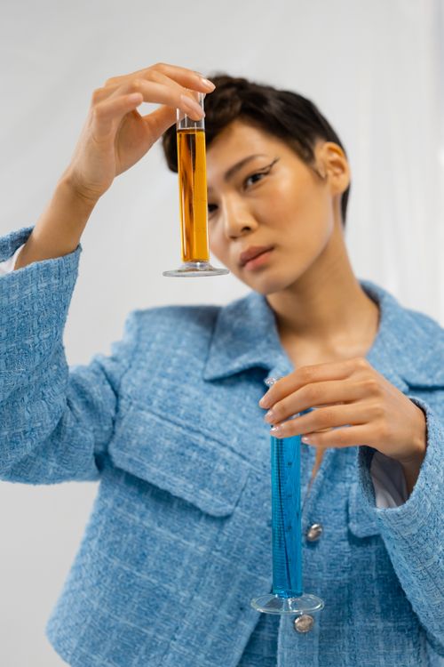 Free Female scientist examining blue and amber liquids in test tubes, focused in a lab environment. Stock Photo