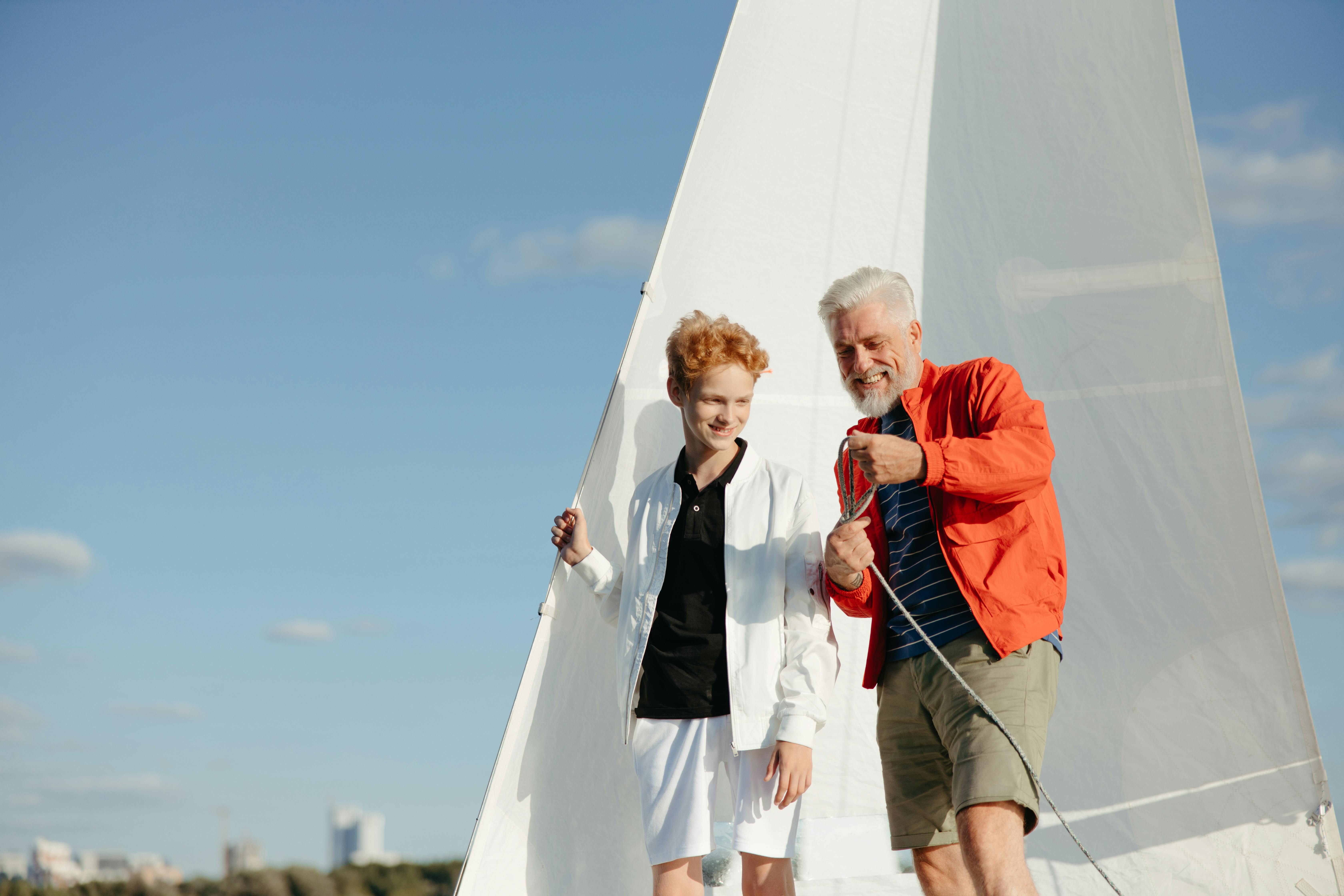 Grandfather and grandson bonding while sailing together on a sunny day. Perfect for family and adventure themes.