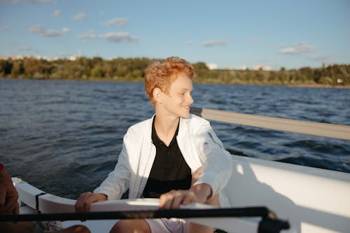 Man in Black Shirt and White Jacket Sitting on White Boat