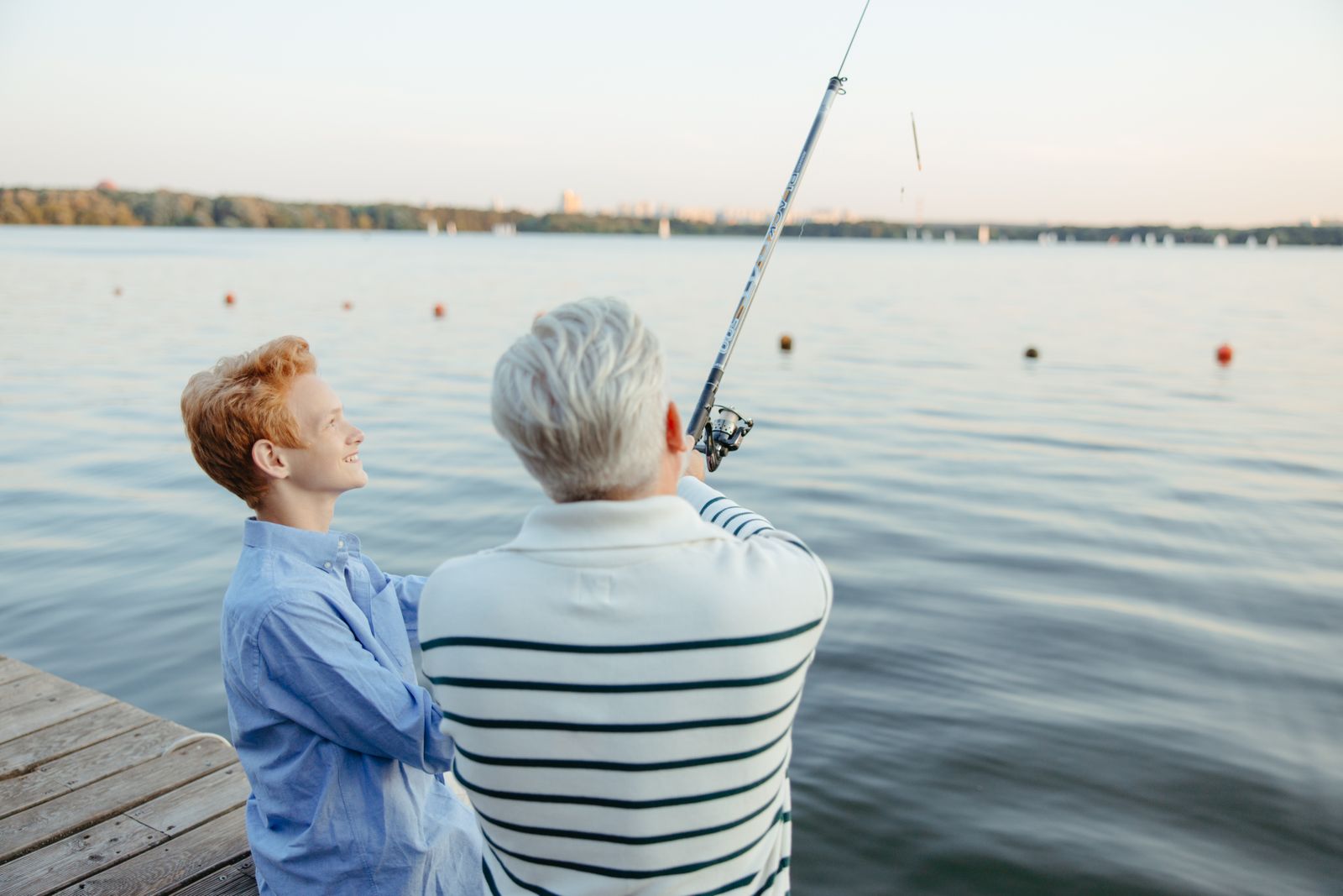 A grandfather and grandson fishing from a dock