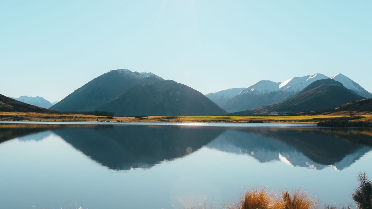 Calm New Zealand lake reflecting snow-capped mountains