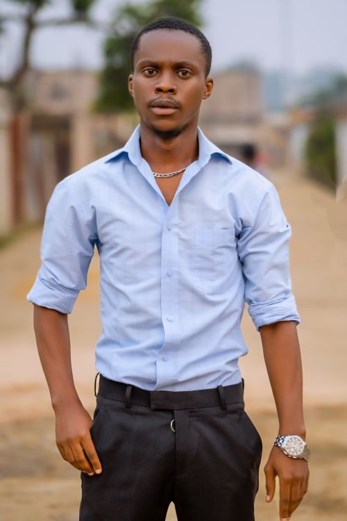 Free Portrait of a young man in a casual blue shirt standing outdoors in Brazzaville. Stock Photo