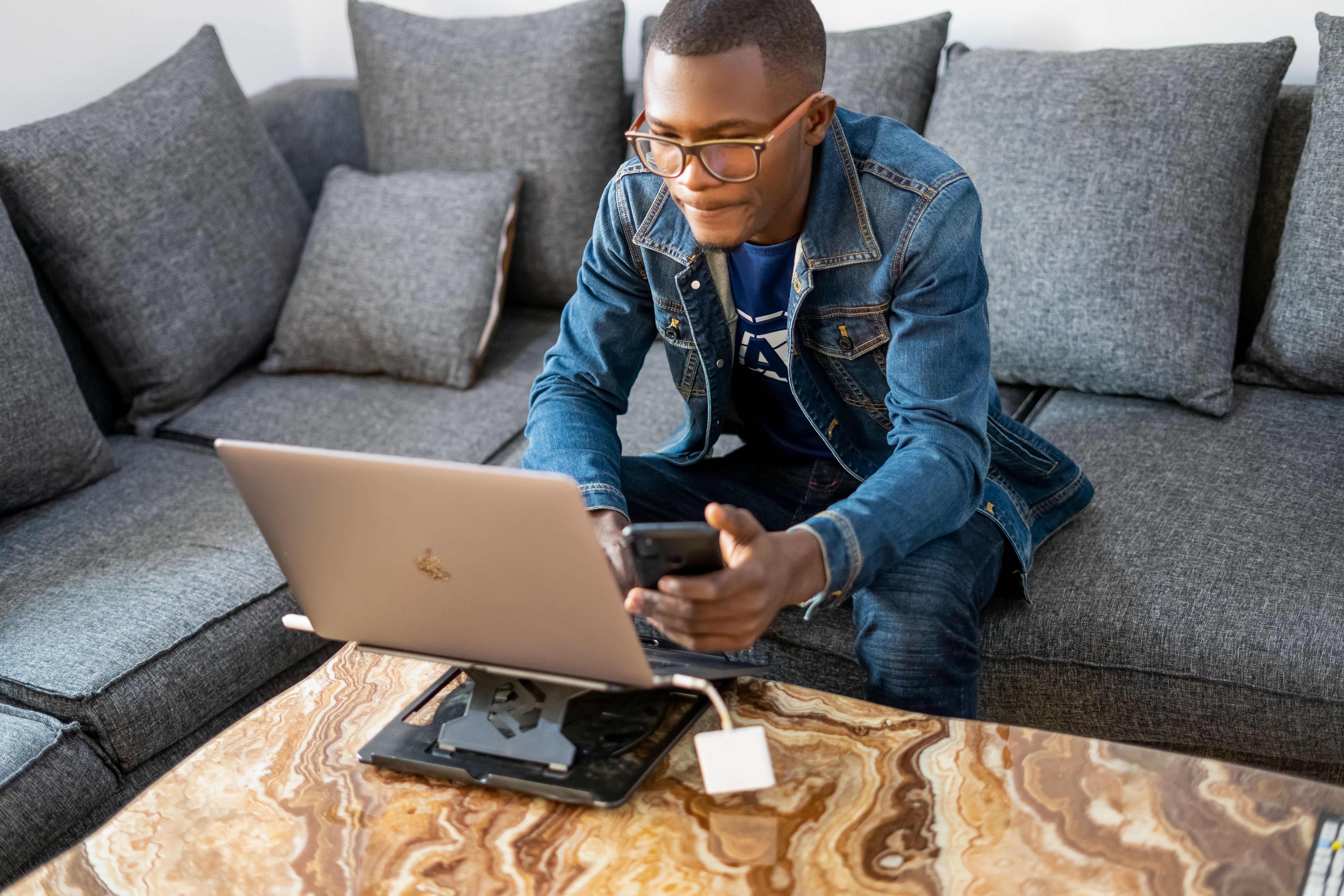 A man holding a smartphone while using a laptop, Angola