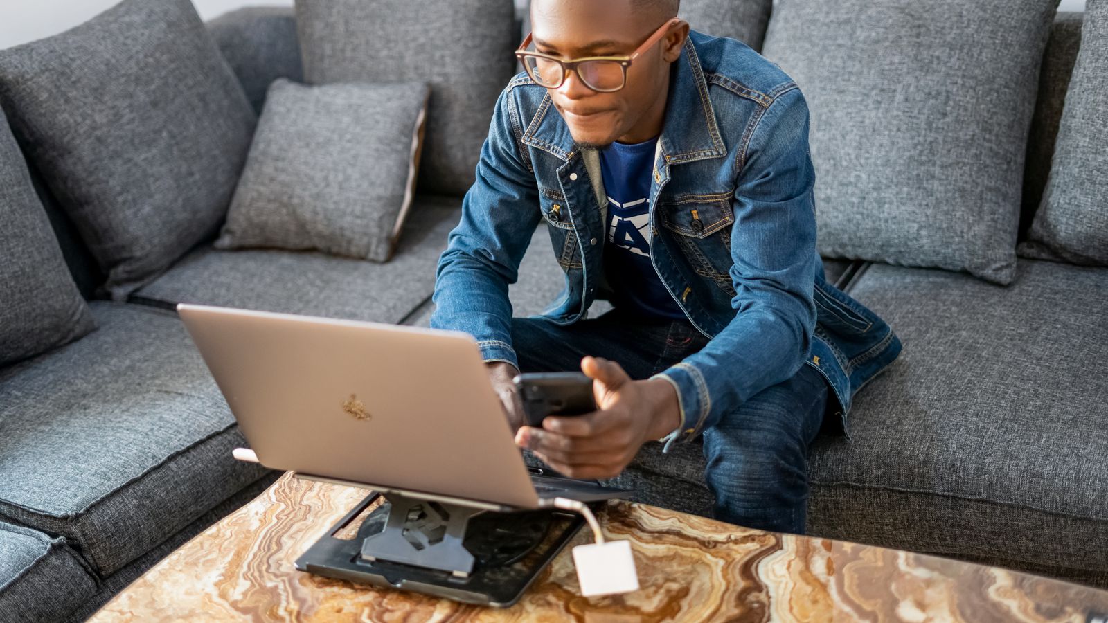 A man holding a smartphone while using a laptop, Angola