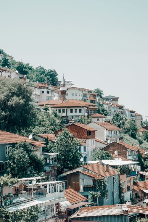 Free Picturesque village on a hillside with red-roofed houses and lush greenery. Stock Photo